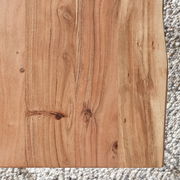 Draufsicht auf eine Tischplatte aus Holz mit natürlicher Maserung und Knoten, auf einem Teppich liegend.