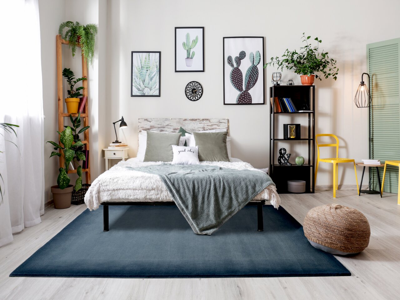 Gemütliches Schlafzimmer mit modernem Dekor, Pflanzen und einem großen, blauen Teppich in der Mitte des Raumes, aus der Perspektive von vorne betrachtet.