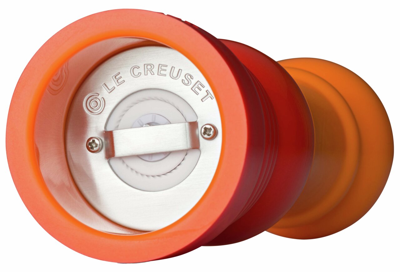Nahaufnahme der Unterseite einer ofenroten Pfeffermühle mit sichtbarem Mahlwerk und Le Creuset Logo.