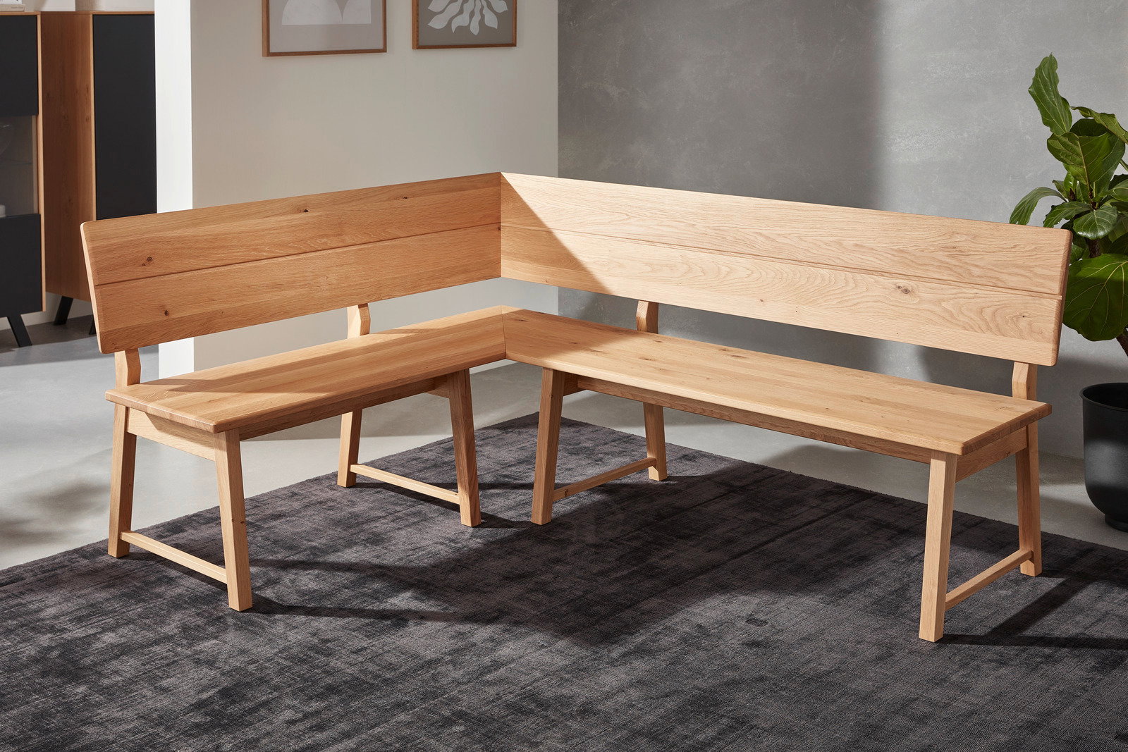 Eckbank aus Holz in L-Form, seitliche Perspektive, auf einem dunklen Teppich in modernem Raum