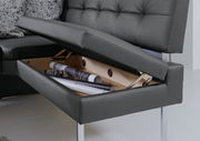 Nahaufnahme einer schwarzen Eckbank mit Stauraum unter der Sitzfläche, die teilweise geöffnet ist. Die Perspektive zeigt den Stauraum von der Seite.