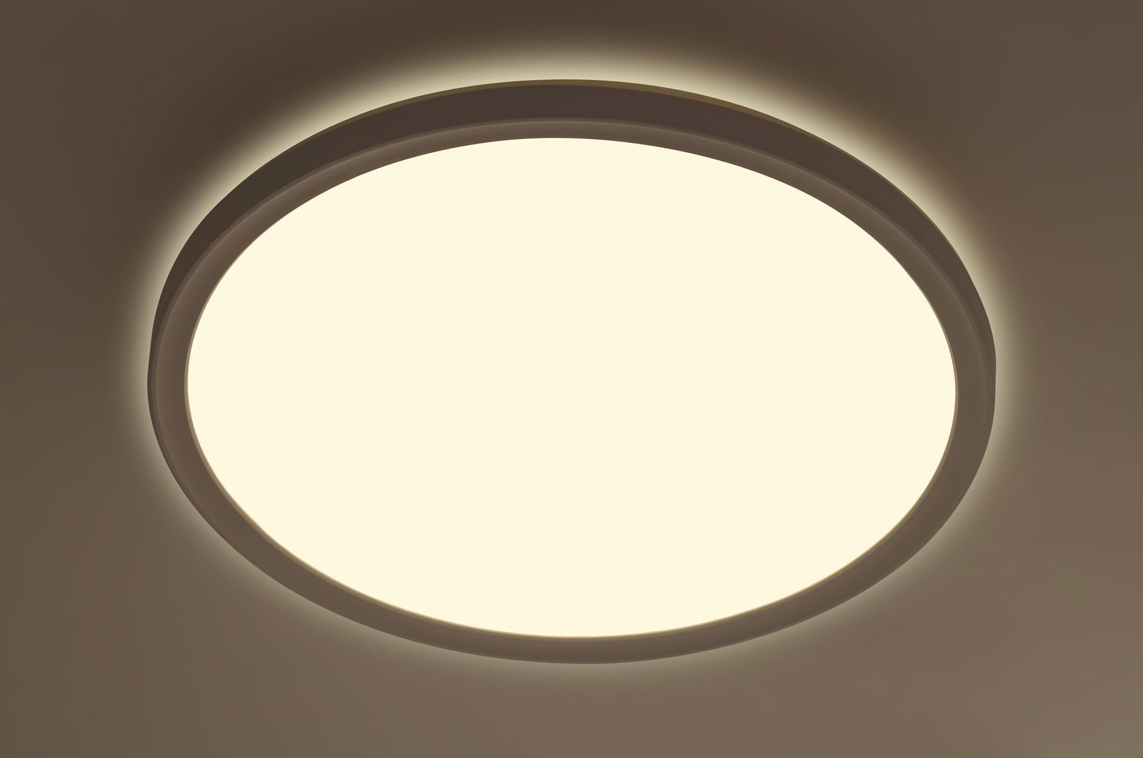 Runde LED-Deckenleuchte aus der Perspektive von unten betrachtet, leuchtend mit warmem Licht.