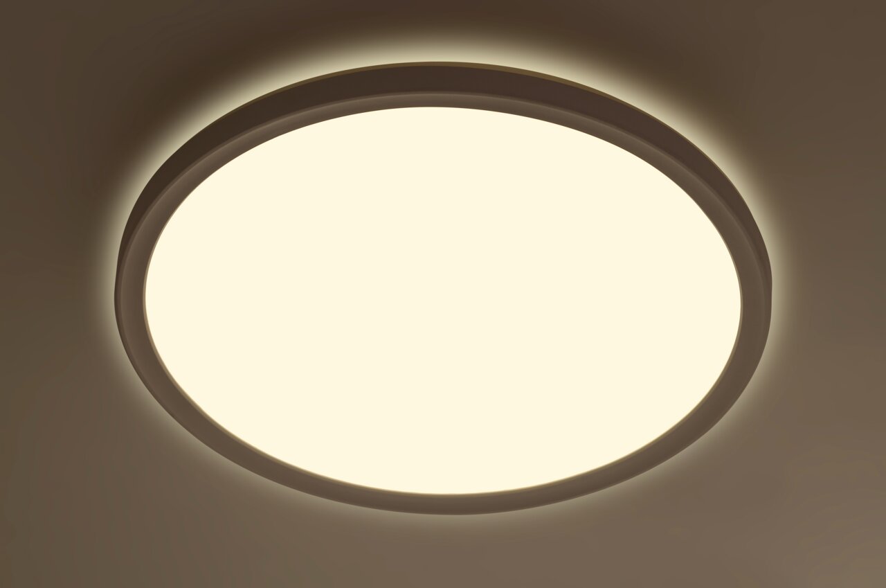 Runde LED-Deckenleuchte aus der Perspektive von unten betrachtet, leuchtend mit warmem Licht.