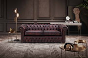 Chesterfield Sofa in einem eleganten Wohnzimmer, frontal betrachtet, mit dunklem Lederbezug und klassischem Design.