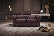 Chesterfield Sofa in einem eleganten Wohnzimmer, frontal betrachtet, mit dunklem Lederbezug und klassischem Design.