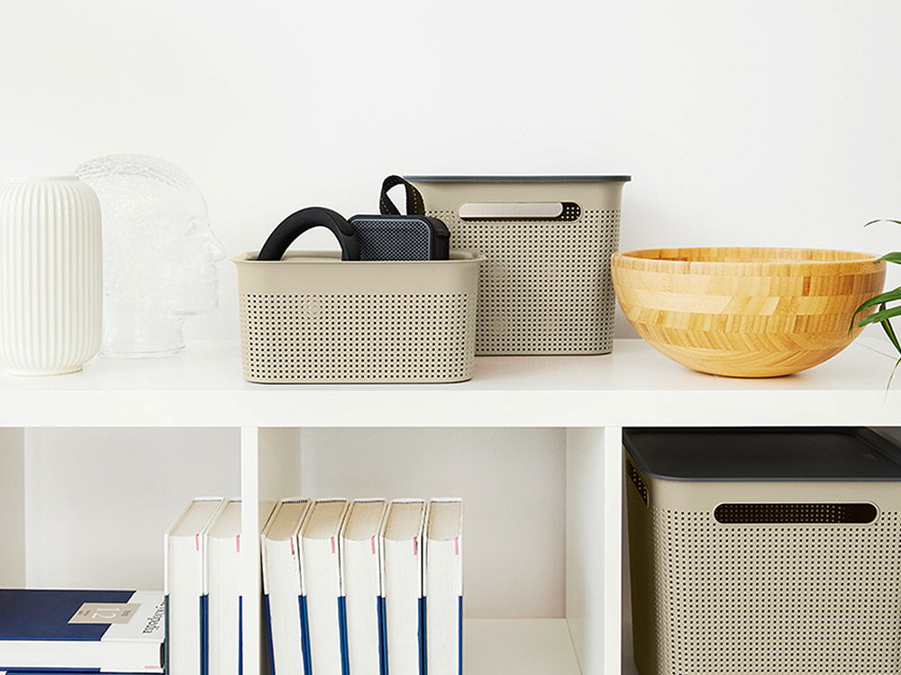 Modernes Regal mit Aufbewahrungsboxen, Büchern und Dekoration in hellen Farben.