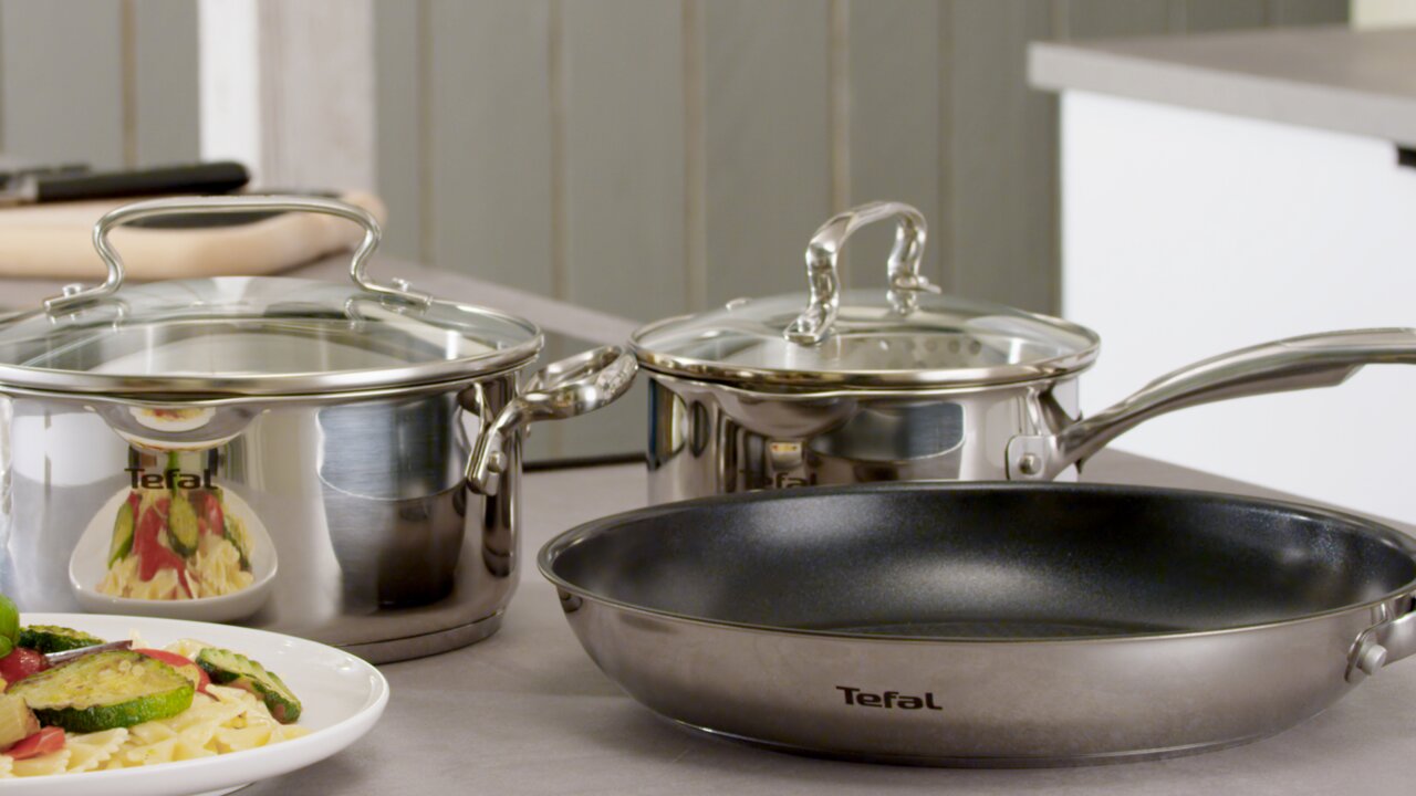 Tefal Pfannenset 3-tlg. 20cm + 24cm + 28cm Pfannenset aus Edelstahl mit Glasdeckeln, bestehend aus drei Töpfen in verschiedenen Größen, auf einer Küchenarbeitsplatte. Perspektive von vorne.