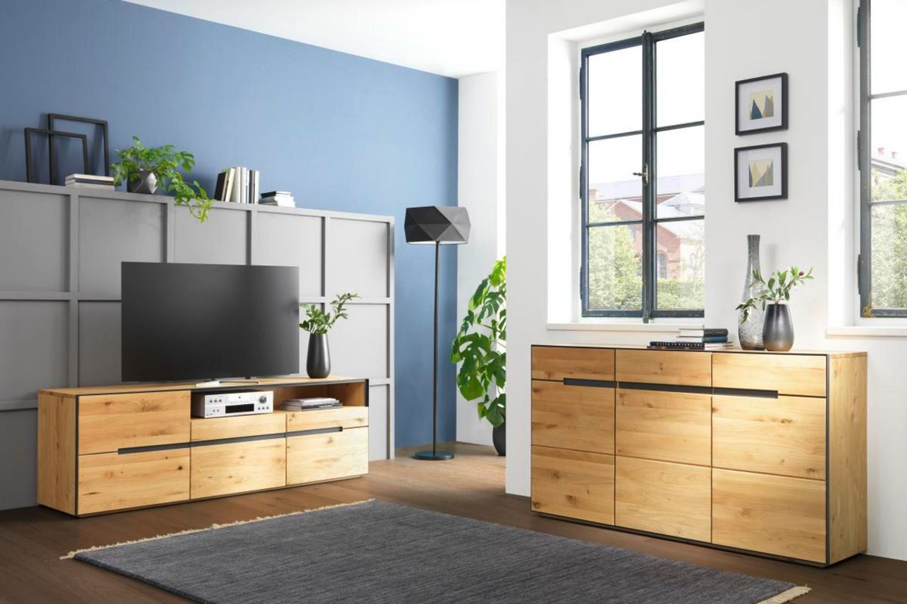 Moderne Wohnzimmermöbel aus Holz, bestehend aus einem TV-Lowboard und einem Sideboard, in einem hellen Raum mit blauen und weißen Wänden, seitliche Perspektive.