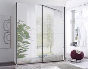 Moderne kledingkast met grote spiegeldeuren en zwarte handgrepen in een lichte slaapkamer, vooraanzicht licht schuin van rechts