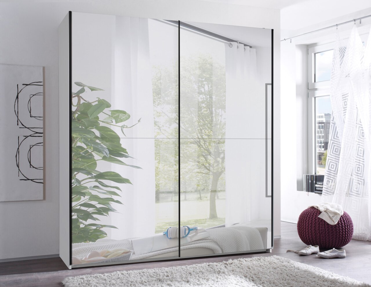 Moderne kledingkast met grote spiegeldeuren en zwarte handgrepen in een lichte slaapkamer, vooraanzicht licht schuin van rechts
