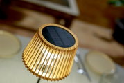 Nahaufnahme einer Solar-Tischleuchte mit Holzlamellen und Solarpanel von oben betrachtet.