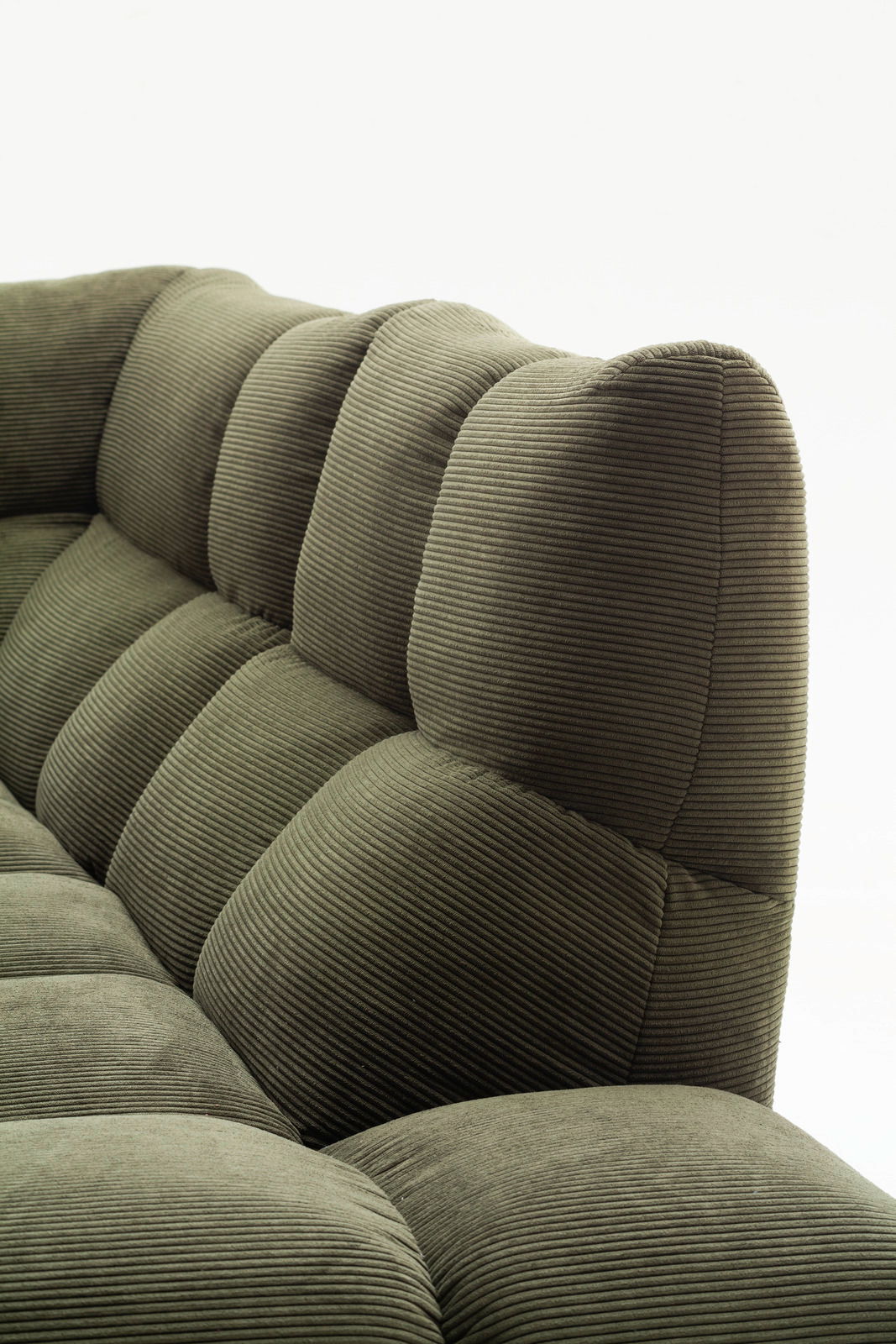 Nahaufnahme einer grünen Eckgarnitur mit geripptem Stoffbezug, seitliche Perspektive