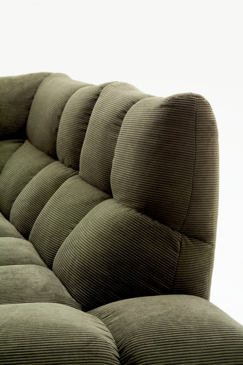 Nahaufnahme einer grünen Eckgarnitur mit geripptem Stoffbezug, seitliche Perspektive