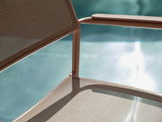 Nahaufnahme eines Stapelsessels mit Metallrahmen und Netzbespannung, im Hintergrund ein verschwommener Pool.