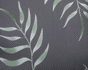 Nahaufnahme einer Niederlehnerauflage mit grünem Blattmuster auf grauem Hintergrund, von oben betrachtet.