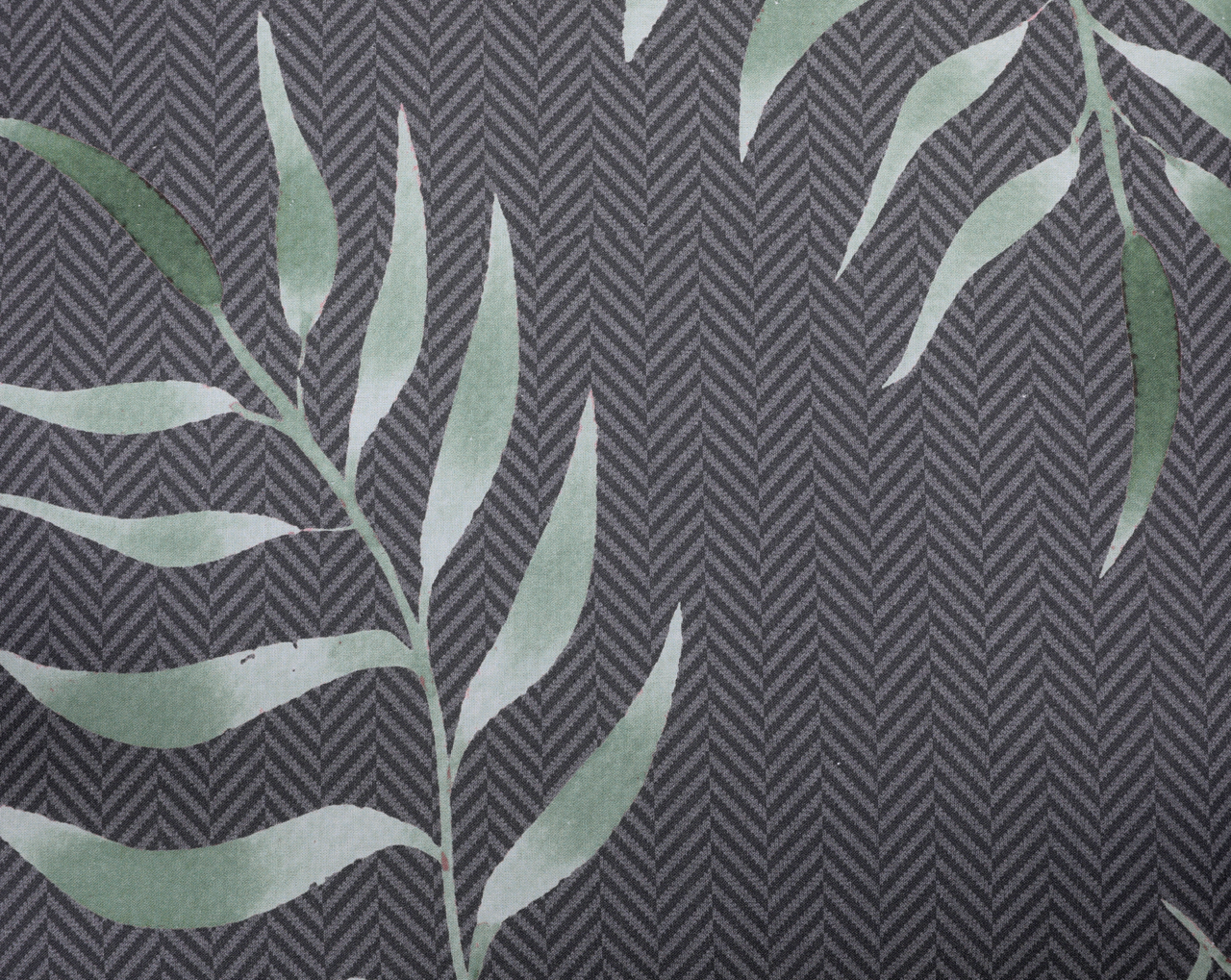 Nahaufnahme einer Niederlehnerauflage mit grünem Blattmuster auf grauem Hintergrund, von oben betrachtet.