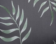 Nahaufnahme einer Niederlehnerauflage mit grünem Blattmuster auf grauem Hintergrund, von oben betrachtet.