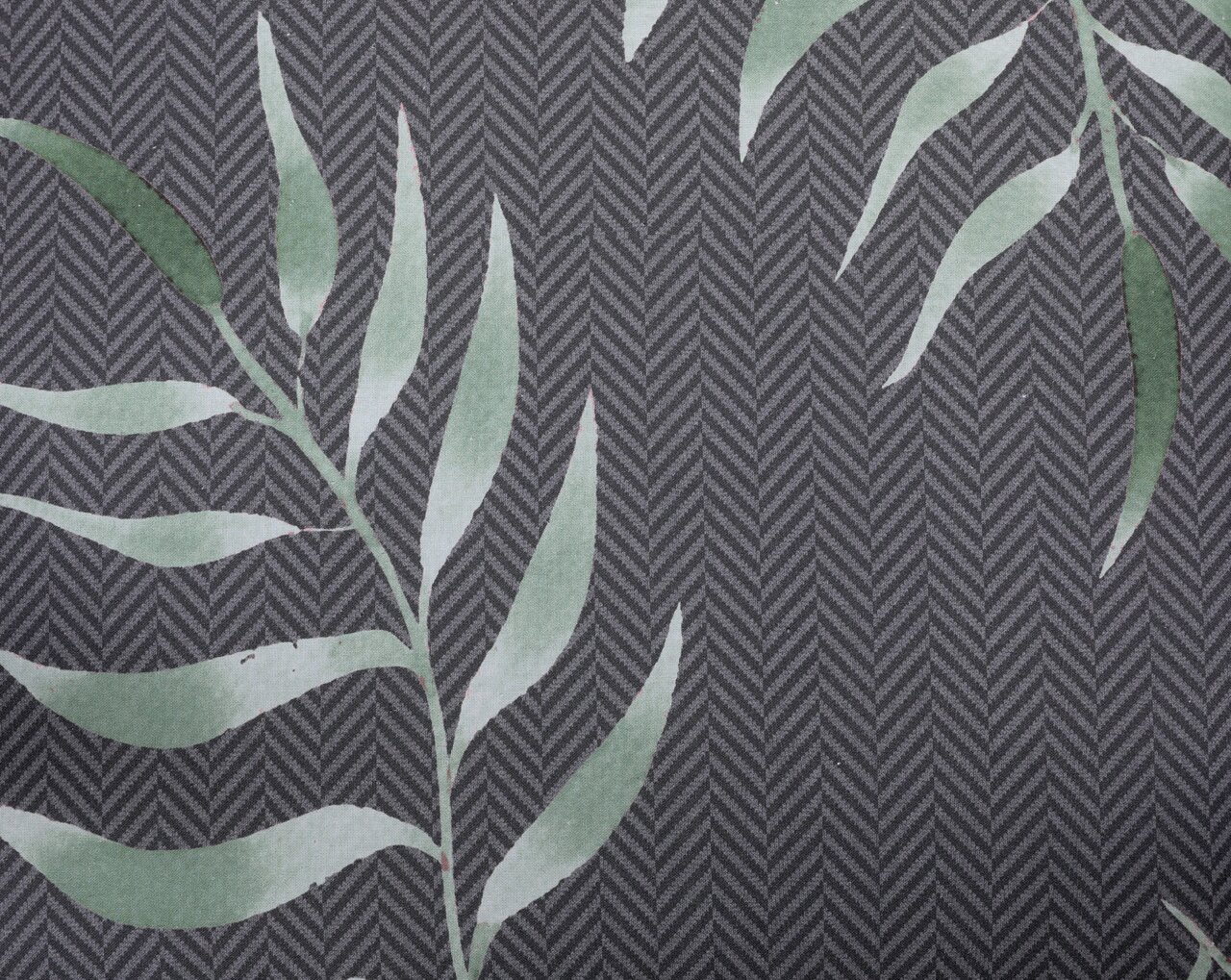 Nahaufnahme einer Niederlehnerauflage mit grünem Blattmuster auf grauem Hintergrund, von oben betrachtet.