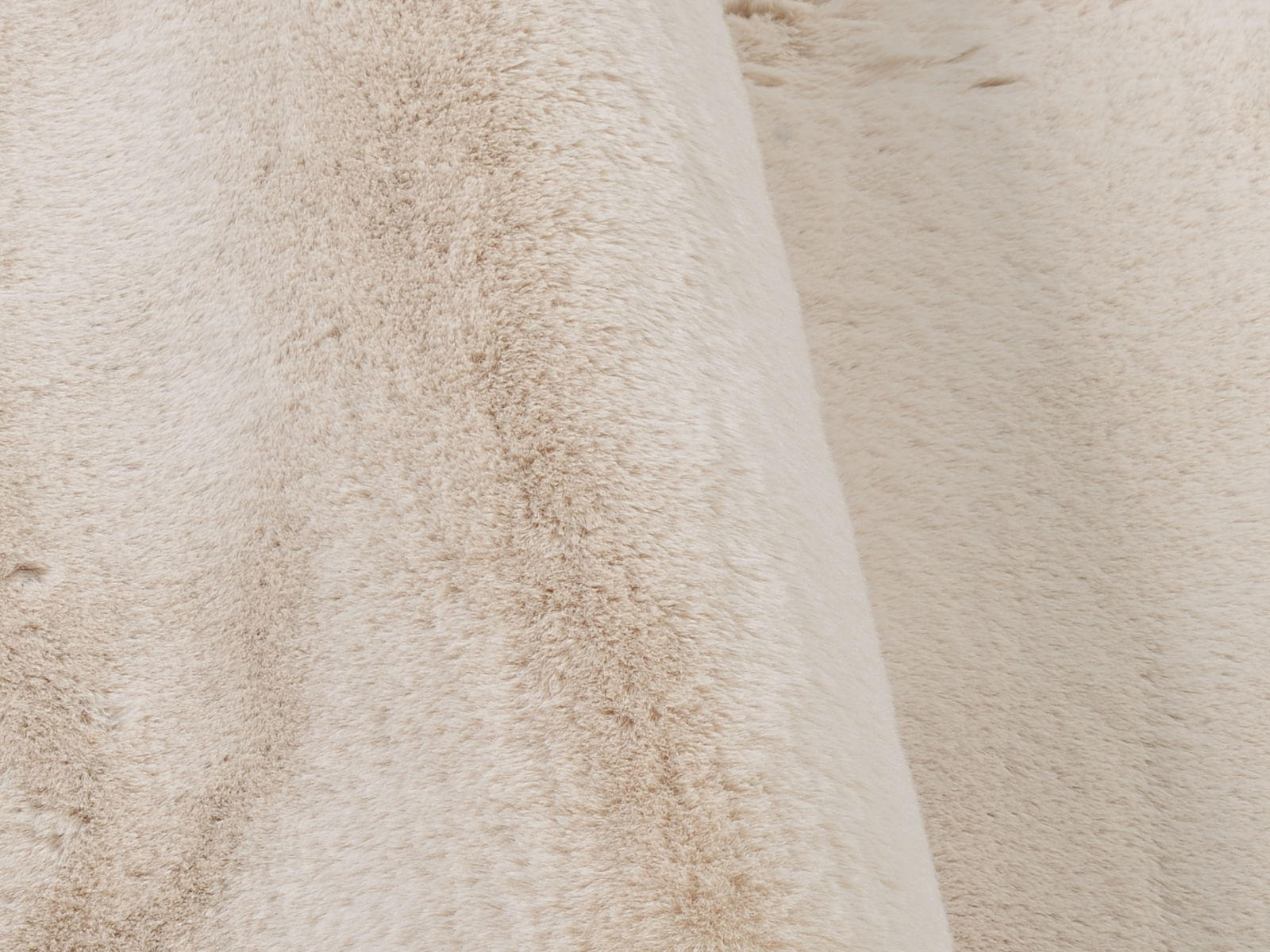 Nahaufnahme eines beigen Fellteppichs mit weicher, flauschiger Textur.