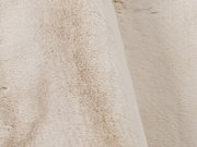 Nahaufnahme eines beigen Fellteppichs mit weicher, flauschiger Textur.