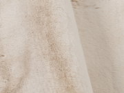 Nahaufnahme eines beigen Fellteppichs mit weicher, flauschiger Textur.