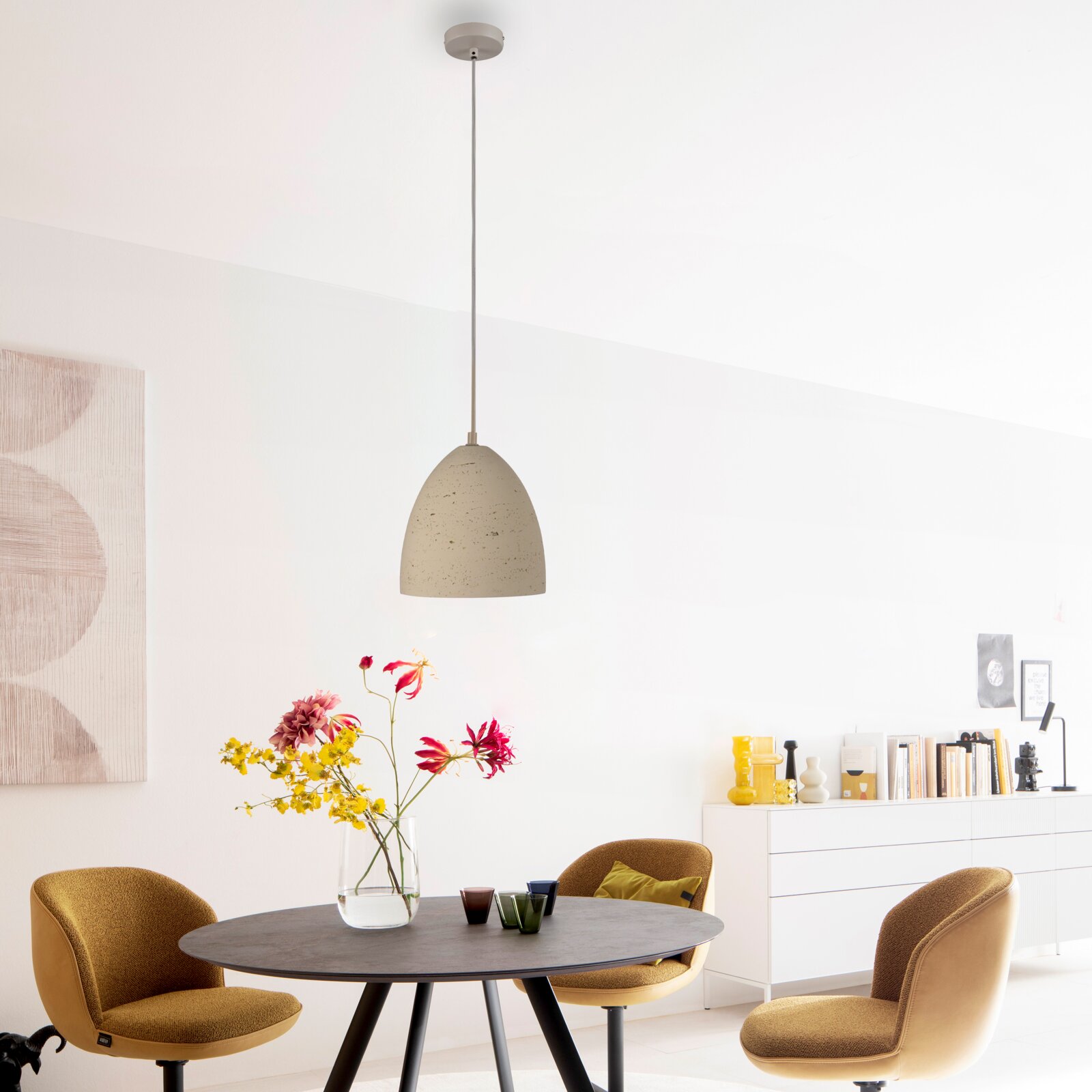 Beige Pendelleuchte mit gesprenkeltem, halbrundem Schirm an langem Kabel über einem Esstisch in modernem Wohnraum, frontale Ansicht in leichtem Untersichtwinkel.