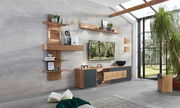 Moderne Wandkombination Valnatura LAGO in einem hellen Wohnzimmer mit großen Fenstern, bestehend aus hölzernen Regalen und Schränken mit dekorativen Elementen. Perspektive von schräg vorne.