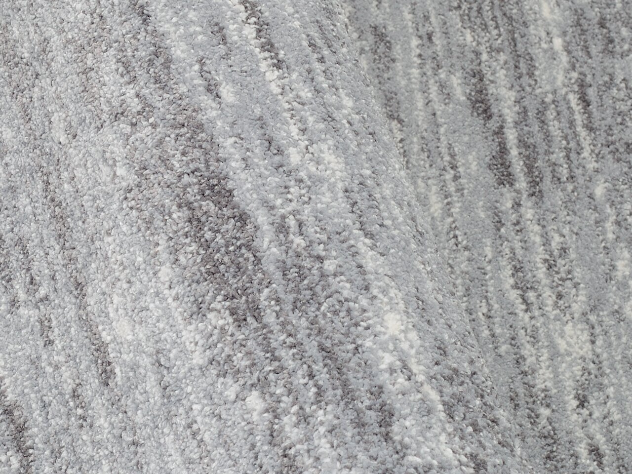 Nahaufnahme eines Uni-Teppichs in Grautönen mit weicher, flauschiger Textur.