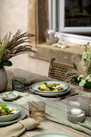 Dipschälchen auf einem gedeckten Tisch im Freien, umgeben von Geschirr und Dekorationen, aus der Vogelperspektive fotografiert.