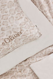 Nahaufnahme einer Satinbettwäsche in Beige mit dezentem Muster und s.Oliver-Logo, von oben fotografiert.