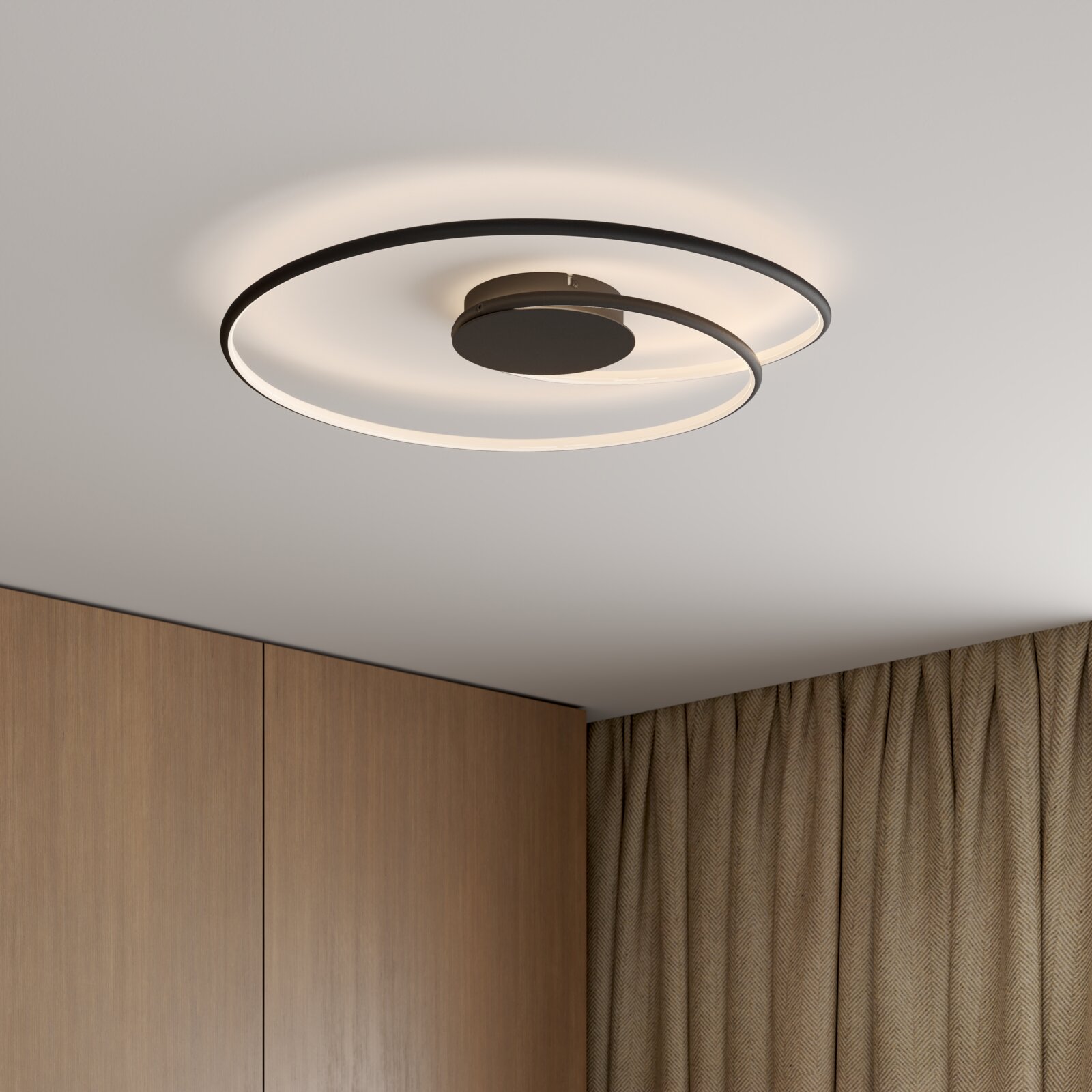 Novel LED-Deckenleuchte BIRMINGHAM Moderne schwarze LED-Deckenleuchte mit zwei überlappenden Ringelementen und warmweißem Licht, montiert an der Zimmerdecke; Perspektive: leicht von unten schräg aufgenommen.