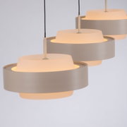 Drie moderne, cilindervormige hanglampen in wit met warm, diffuus licht; zijaanzicht vanuit een licht schuin perspectief tegen een lichte achtergrond