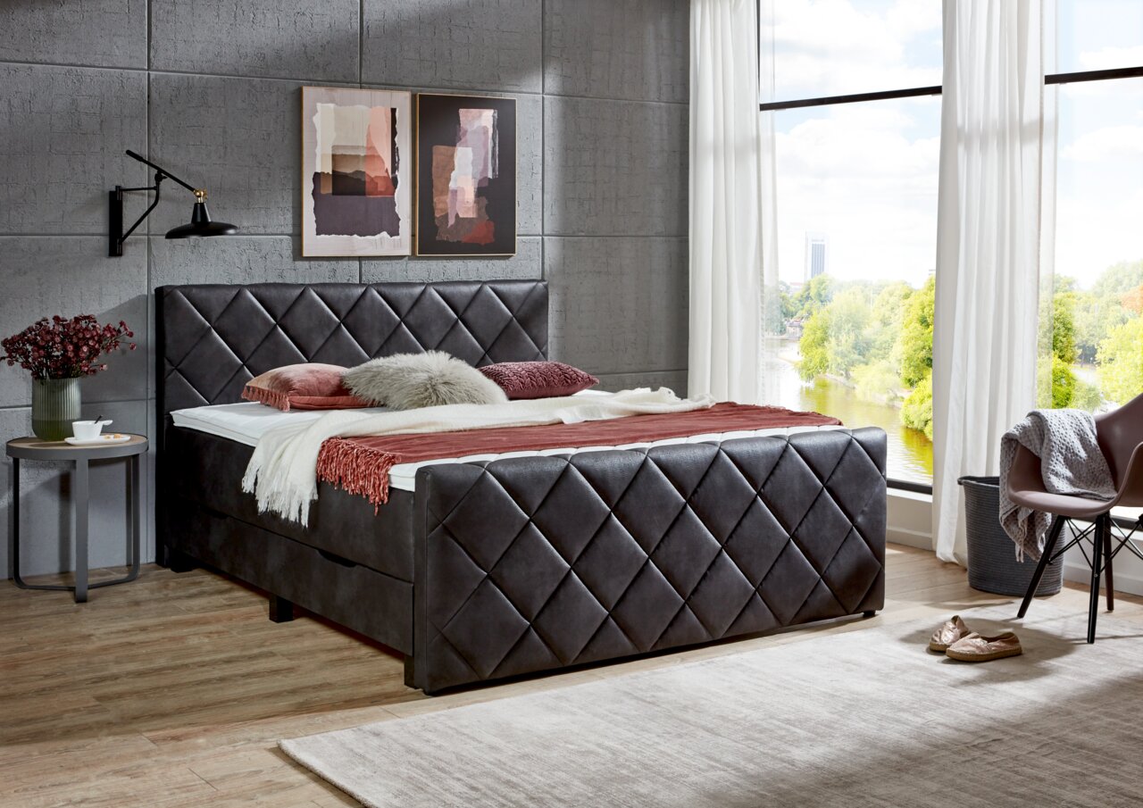 Boxbett mit gestepptem Kopf- und Fußteil in einem modernen Schlafzimmer, seitliche Perspektive