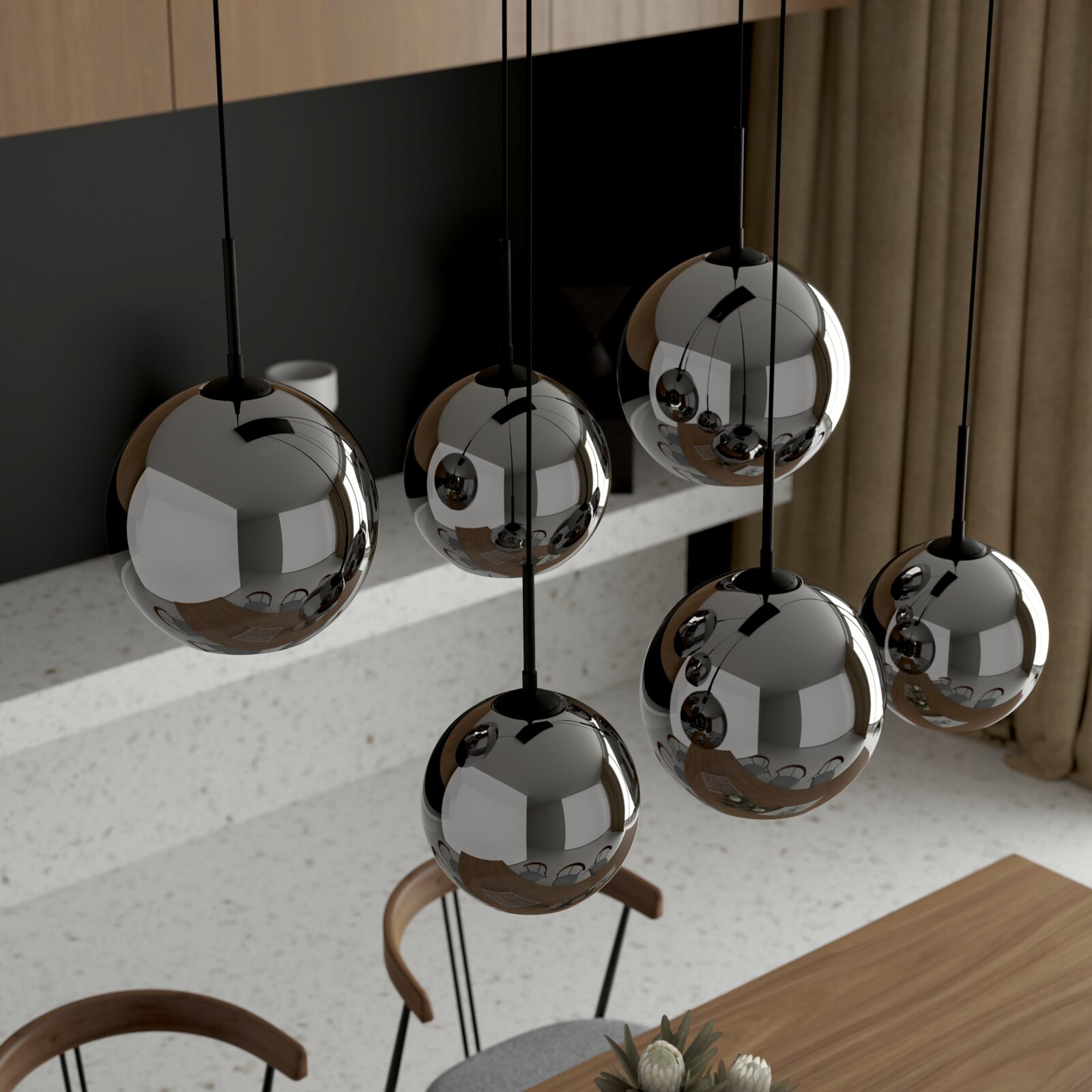 Schwarze Pendelleuchte mit mehreren spiegelnden Kugel-Schirmen aus Metall, hängend über einem Esstisch in modernem Interieur, schräg von oben aus der Seitenansicht aufgenommen