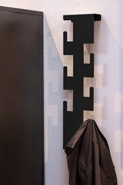 Moderne schwarze Wandgarderobe mit geometrischem Design, seitliche Perspektive, mit aufgehängtem Mantel.