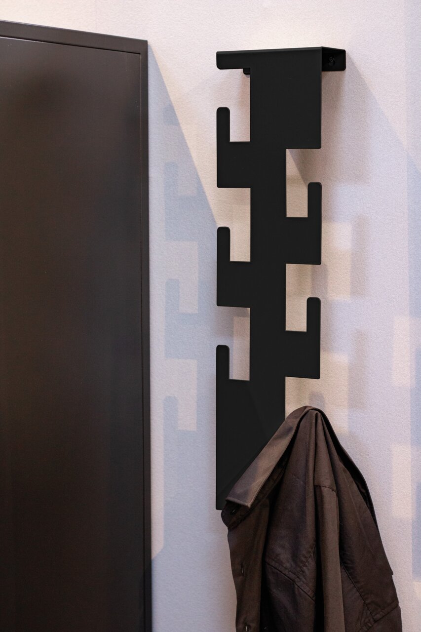 Zurbrüggen Wandgarderobe LUNIS Moderne schwarze Wandgarderobe mit geometrischem Design, seitliche Perspektive, mit aufgehängtem Mantel.