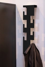 Moderne schwarze Wandgarderobe mit geometrischem Design, seitliche Perspektive, mit aufgehängtem Mantel.