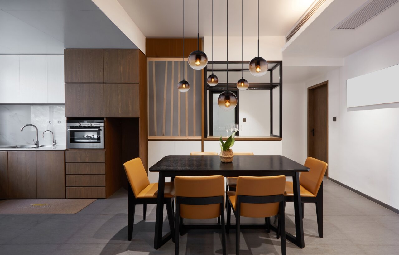 Moderne Hängeleuchte über einem Esstisch mit sechs Glühbirnen, in einem stilvollen Esszimmer mit Holz- und Metallelementen, aus der Perspektive des Raumes betrachtet.