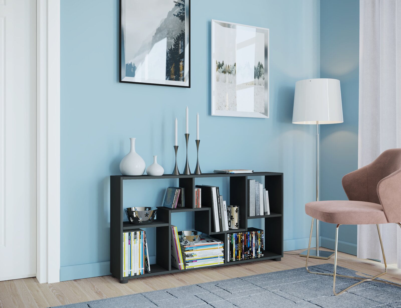 Schwarzes, niedriges Regal mit asymmetrischen Fächern und Büchern, dekoriert mit weißen Vasen und Kerzenhaltern, im modernen Wohnzimmer vor hellblauer Wand – Perspektive: frontale Ansicht mit leichtem Blick von rechts.