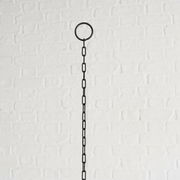 Schwarze Metallkette mit Ring, vor weißer Ziegelwand, von unten nach oben fotografiert