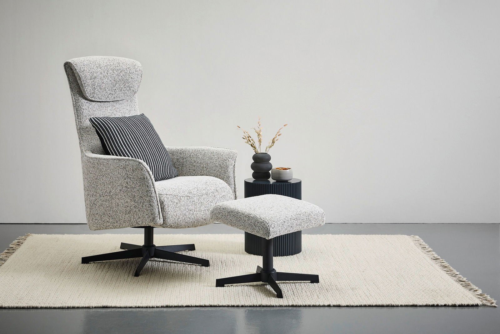 Welnova Relaxsessel mit Hocker VICTORIA Seitenansicht eines modernen Relaxsessels mit Hocker auf einem Teppich, begleitet von einem kleinen Beistelltisch mit Dekoration.