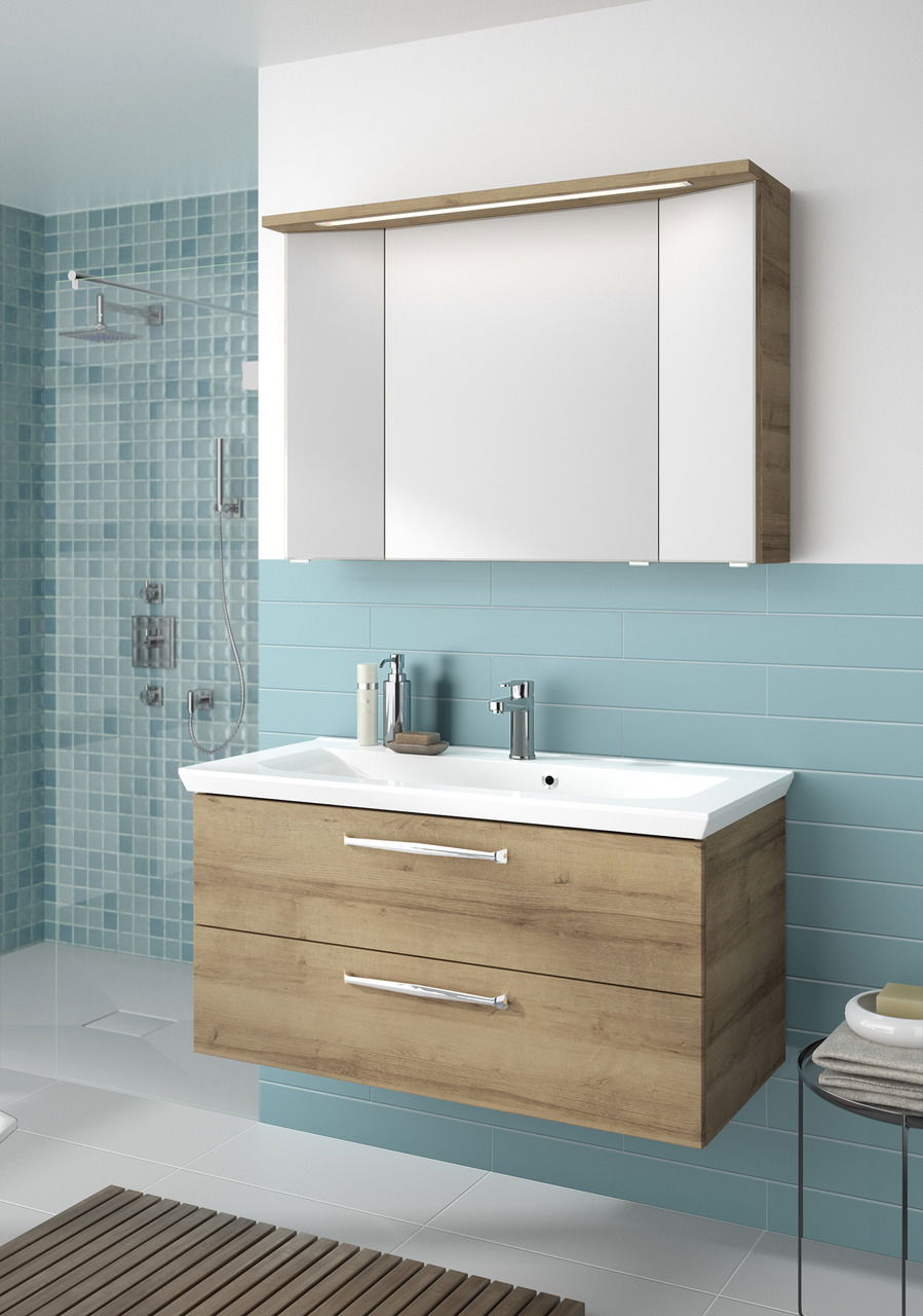 Moderner Badblock mit Holzoptik und weißem Waschbecken, frontal betrachtet, vor einer türkisfarbenen Fliesenwand.