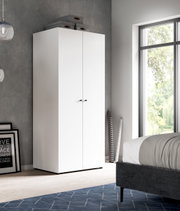 Weißer, hoher zweitüriger Kleiderschrank mit schwarzen Griffen im Schlafzimmer, frontale Ansicht mit leichter Perspektive von links