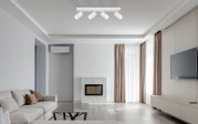 Moderne witte plafondspot met vier verstelbare spots in een stijlvolle woonkamer, gezien van onderaf.