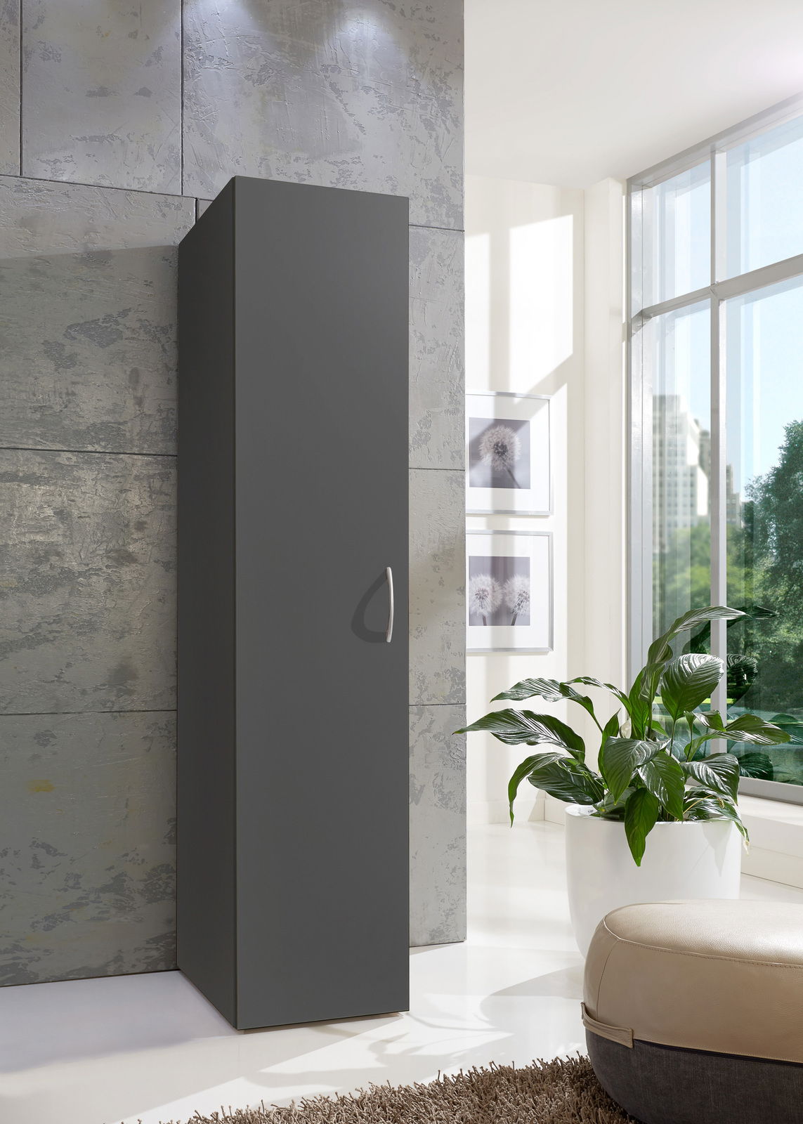 Moderner, schmaler Kleiderschrank in dunklem Grau, seitliche Perspektive, in einem hellen Raum mit großen Fenstern und Pflanzen.