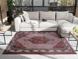 Orientteppich in einem modernen Wohnzimmer, von oben betrachtet, mit einem beigen Sofa und Pflanzen im Hintergrund.