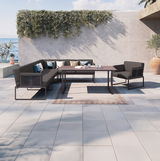 Moderne Loungegarnitur mit großem Loungetisch und Loungesesseln auf einer Terrasse mit Meerblick, seitliche Perspektive.