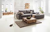 Graues Ecksofa INFERNO in modernem Wohnzimmer, Perspektive von vorne rechts, mit Holztisch und Dekoration.
