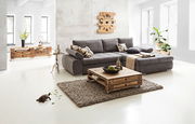 Graues Ecksofa INFERNO in modernem Wohnzimmer, Perspektive von vorne rechts, mit Holztisch und Dekoration.