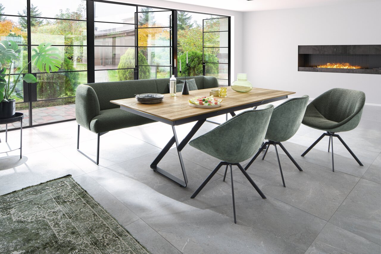Moderne Esszimmerbank in einem hellen Raum mit großen Fenstern, neben einem Holztisch und stilvollen Stühlen, aus seitlicher Perspektive.
